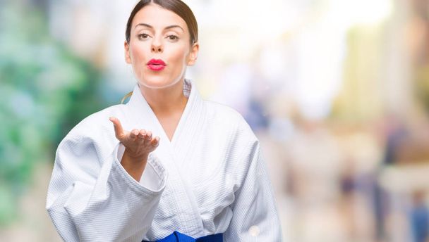 Fiatal gyönyörű nő visel karate kimonó egységes át nézi a kamerát egy csókot kézzel fúj a levegő, szép és szexi, hogy elszigetelt háttér. Szeretet kifejezése. - Fotó, kép