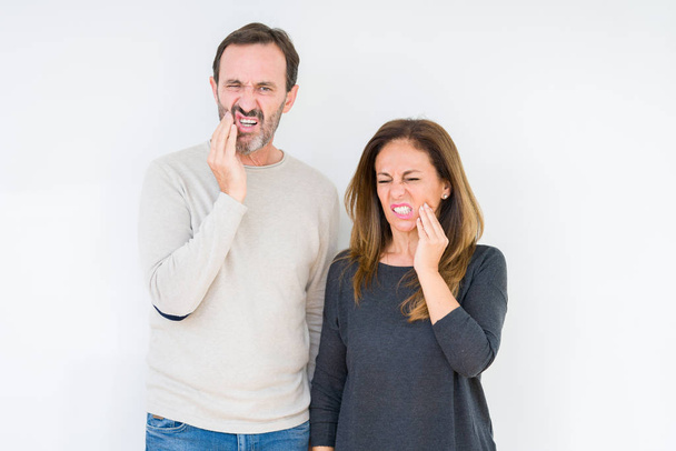 Όμορφη μέση ηλικία ζευγάρι στην αγάπη πέρα από το απομονωμένο υπόβαθρο αγγίζοντας το στόμα με το χέρι με επώδυνη έκφραση λόγω πονόδοντος ή οδοντική ασθένεια στα δόντια. Οδοντίατρος έννοια. - Φωτογραφία, εικόνα