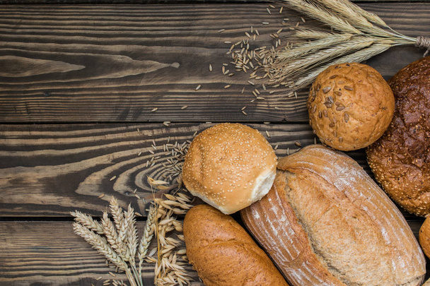 Freshly baked bread products on wooden background - Photo, image