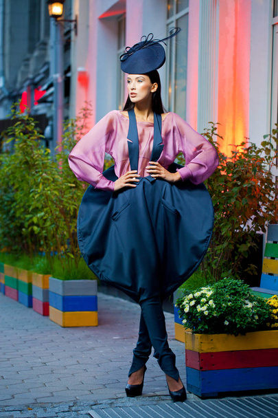 Young beautiful model in a stylish designer clothes posing on the street in the evening - Fotó, kép