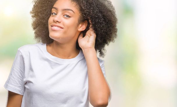 Fiatal afro-amerikai nő mosolyogva kézzel fülbe hallgat tárgyalást pletyka vagy pletyka elszigetelt háttérhez képest. Süketség koncepció. - Fotó, kép