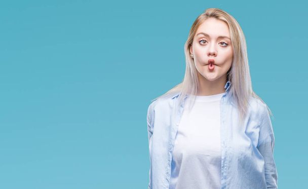 Jonge blonde vrouw over geïsoleerde achtergrond maken vis gezicht met lippen, gek en komische gebaar. Grappige expressie. - Foto, afbeelding
