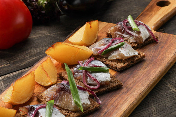 herring with baked potatoes and onions on tray on wooden background. Restaurant dish - Photo, image