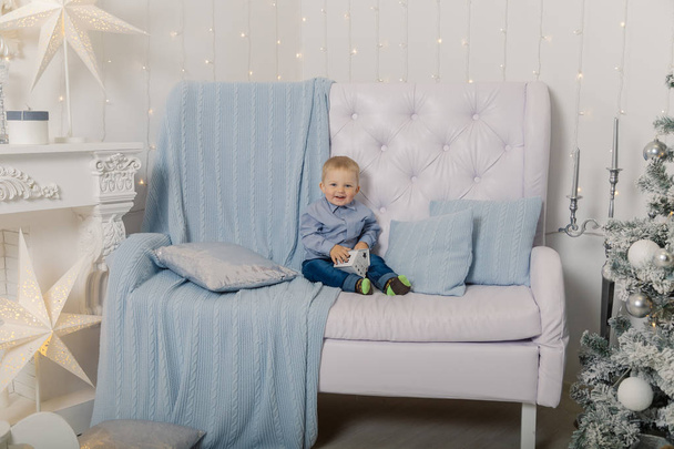Маленький мальчик на диване в новогоднем декоре. Новый 2019 год
. - Фото, изображение