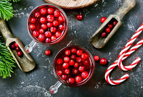 top view of christmas candy canes and cranberry drinks with berries on dark tabletop - Foto, Bild
