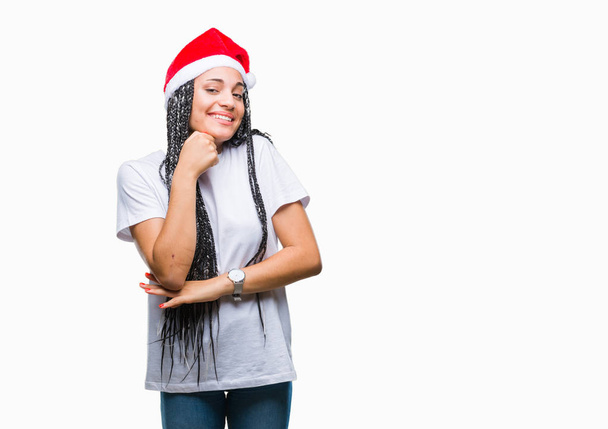 若者は、あごを考えて質問、物思いにふける式の手で隔離された背景にクリスマスの帽子をかぶって髪アフリカ系アメリカ人少女を編組。思いやりのある顔をして笑っています。疑いのコンセプト. - 写真・画像