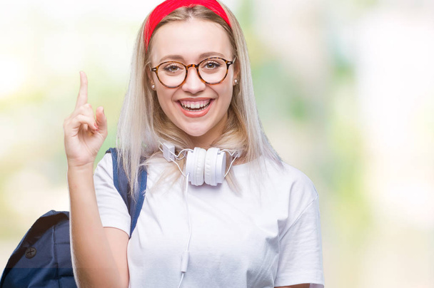 Fiatal szőke diák nő visel szemüveget és a hátizsák-sikeres ötlet a felfelé mutató ujj elszigetelt háttérhez képest. Kilépett, és boldog. Számú. - Fotó, kép
