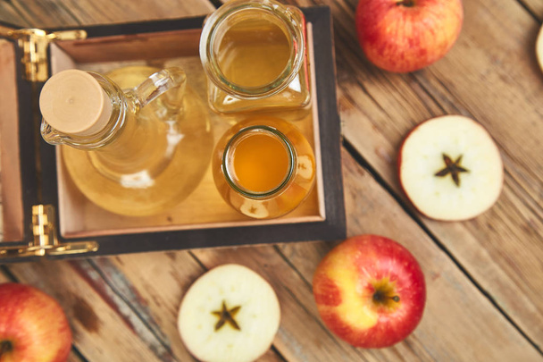 Vinagre de manzana. Botella de vidrio de vinagre orgánico de manzana sobre mesa de madera. Alimento orgánico saludable. Botella de sidra fresca cerca de manzanas rojas de otoño. Fondo rústico, Vista superior Espacio para texto
 - Foto, Imagen