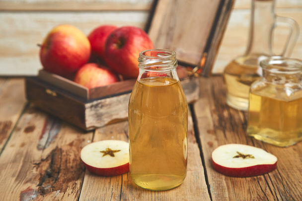 Vinagre de manzana. Botella de vidrio de vinagre orgánico de manzana sobre mesa de madera. Alimento orgánico saludable. Botella de sidra fresca cerca de manzanas rojas de otoño. Fondo rústico, Espacio para texto
 - Foto, imagen