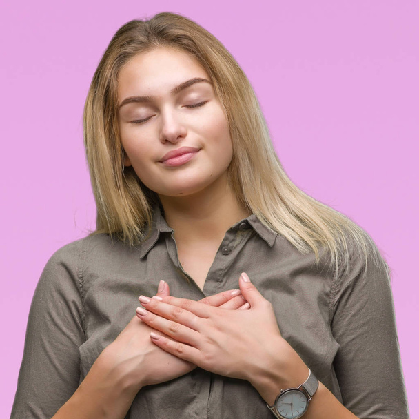Young caucasian business woman over isolated background smiling with hands on chest with closed eyes and grateful gesture on face. Health concept. - Foto, Bild