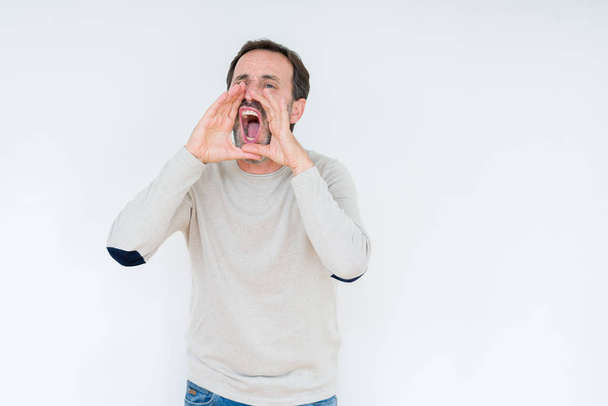 Elegante senior man over geïsoleerde achtergrond schreeuwen hardop vertoornd zijn voor handen over mond - Foto, afbeelding