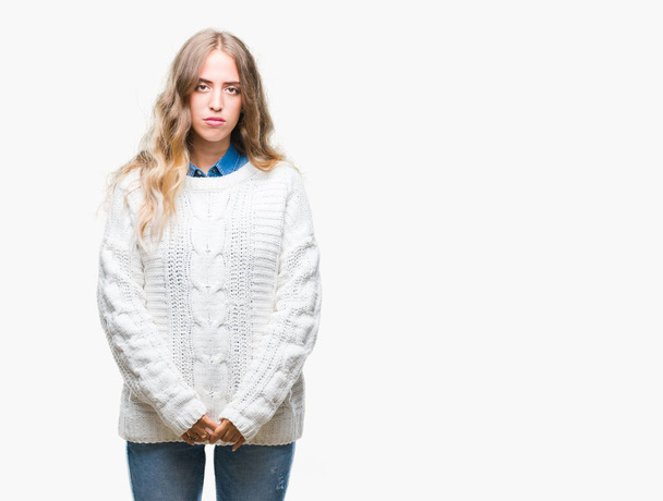 Όμορφη νεαρή ξανθιά γυναίκα, φορώντας χειμώνα πουλόβερ πάνω από απομονωμένες φόντο με τη σοβαρή έκφραση στο πρόσωπο. Απλές και φυσικές κοιτάζοντας την κάμερα. - Φωτογραφία, εικόνα