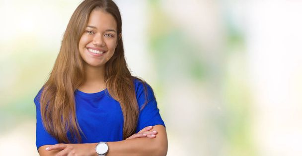 Mladá krásná bruneta žena nosí modré tričko přes samostatný pozadí šťastný obličej s úsměvem překřížené paže při pohledu na fotoaparát. Pozitivní člověk. - Fotografie, Obrázek