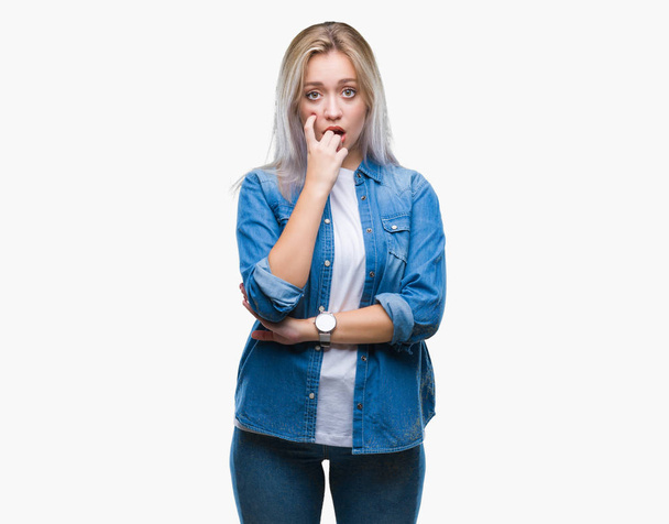 Giovane donna bionda su sfondo isolato cercando stressato e nervoso con le mani in bocca mordere le unghie. Problema di ansia
. - Foto, immagini
