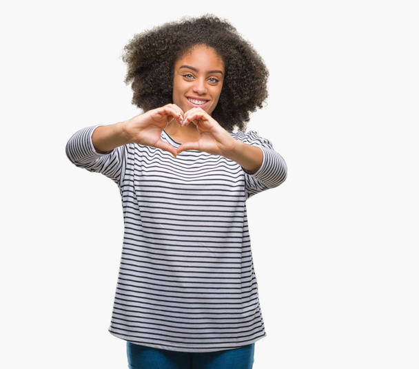 Mujer afroamericana joven sobre fondo aislado sonriendo en el amor mostrando el símbolo del corazón y la forma con las manos. Concepto romántico
. - Foto, imagen