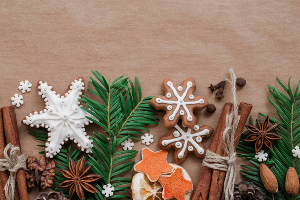 Frame with fir branches, cookies and Christmas decorations on dark brown paper background. Top view. - Fotografie, Obrázek