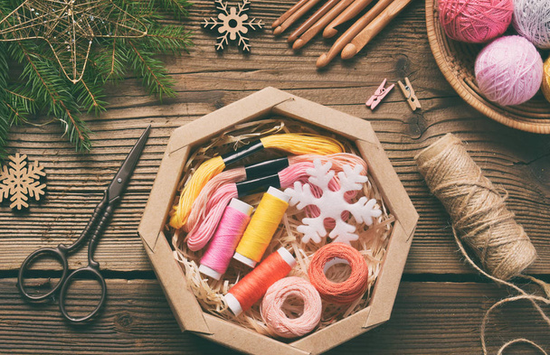Gift wrapping. Present for the needlewoman - thread, floss, needles, hook, cotton yarn. Composition with box, festive decoration and fir tree branch. Merry Christmas and Happy New Year concept. - Photo, Image