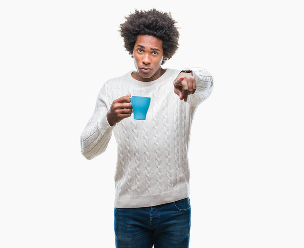 Afro amerikkalainen mies juo kupin kahvia yli eristetty tausta osoittaa sormella kameraan ja sinulle, käsi merkki, positiivinen ja luottavainen ele edestä
 - Valokuva, kuva