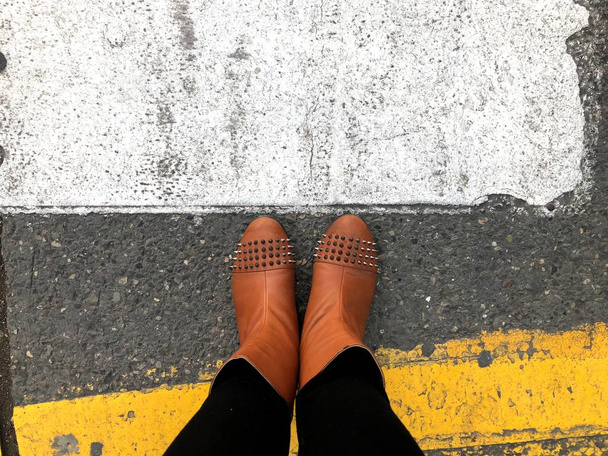 Διάβαση πεζών. Κίτρινα και λευκά χρώματα, στο πεζοδρόμιο και στα πόδια των γυναικών - Φωτογραφία, εικόνα