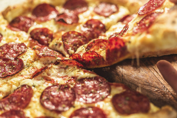 Gorąca pizza z topnienia ser i pepperoni na rustykalne drewnianym stole - Zdjęcie, obraz