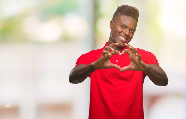 junger afrikanisch-amerikanischer Mann mit isoliertem Hintergrund, der verliebt lächelt und Herz-Symbol und Form mit Händen zeigt. Romantisches Konzept. - Foto, Bild