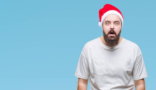 恐れ、驚きの表現、恐怖と興奮した顔でショックを受けて孤立した背景にクリスマスの帽子をかぶって若い白人ヒップ男. - 写真・画像
