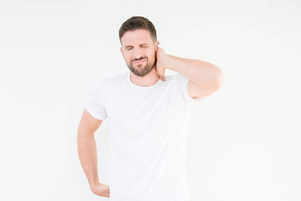 Young handsome man wearing casual white t-shirt over isolated background Suffering of neck ache injury, touching neck with hand, muscular pain - Φωτογραφία, εικόνα