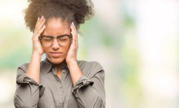 Молодих афро американська жінка в окулярах над ізольованих фону, страждають від головного болю, відчайдушні і підкреслив, тому що біль і мігрень. Руки на голову. - Фото, зображення