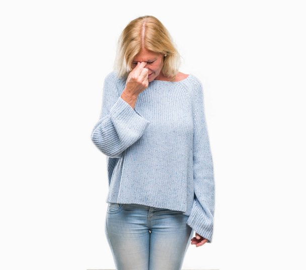 Μέσης ηλικίας ξανθιά γυναίκα, φορώντας χειμώνα πουλόβερ πάνω από απομονωμένες φόντο κουρασμένος τρίβοντας τη μύτη και τα μάτια, αίσθημα κόπωσης και πονοκέφαλο. Άγχος και την απογοήτευση έννοια. - Φωτογραφία, εικόνα