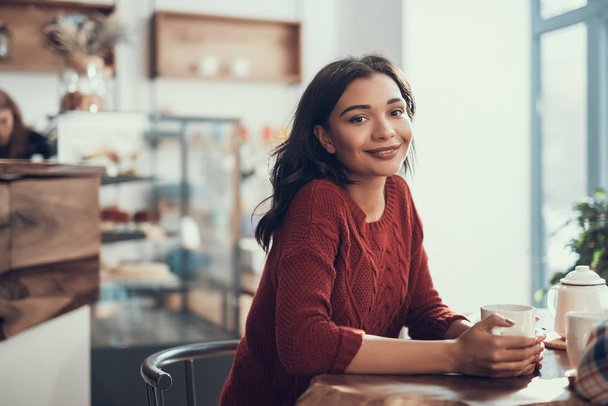 Calm lady sitting at the table of lovely cafe and smiling - Foto, Imagen