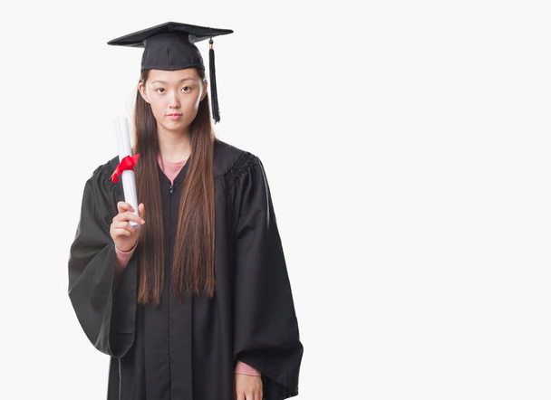 Fiatal kínai nő visel diplomás egységes gazdaság papír mértéke, a Szúró Szembenéz gondolkodás súlyos magabiztos kifejezés - Fotó, kép