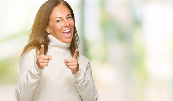 Gyönyörű középkorú felnőtt nő visel téli pulóver, ujjal mutatva a fényképezőgép-val boldog és vicces arc elszigetelt háttérhez képest. Jó energia- és vibrafon. - Fotó, kép