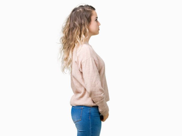 Piękna młoda kobieta blonde noszenie sweatershirt na białym tle patrząc w bok, zrelaksować się poza profil z naturalną twarz uśmiech i pewność siebie. - Zdjęcie, obraz
