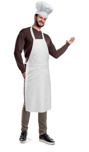 A bearded cook wears an apron and hat and makes an inviting gesture on a white background. - Fotografie, Obrázek