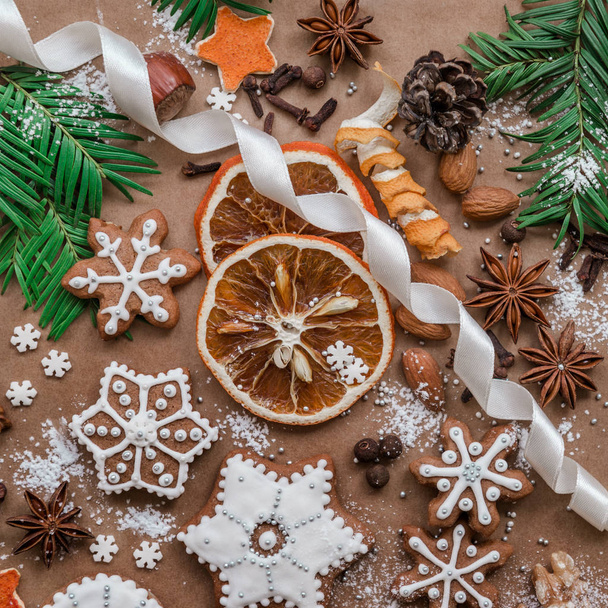 Weihnachtsdekoration mit Gewürzen und Plätzchen in Form von Schneeflocken auf dunkelbraunem Papier Hintergrund. Ansicht von oben. - Foto, Bild