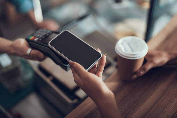 Hand of young lady placing smartphone on credit card payment machine - Φωτογραφία, εικόνα