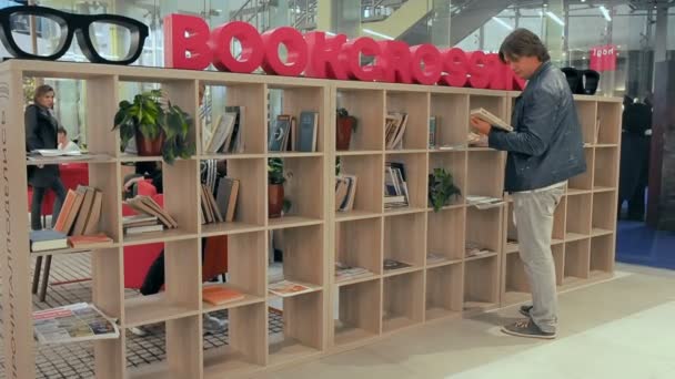 Moscou, Russie - 16 septembre 2018 : Un homme choisit un livre sur l'étagère de BookCrossing. Rayonnage en bois avec des livres pour l'échange entre les gens qui ont fini de lire des livres
 - Séquence, vidéo