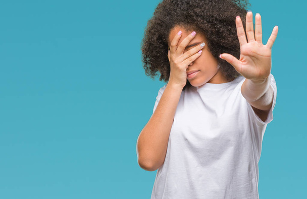 Young afro american woman over isolated background covering eyes with hands and doing stop gesture with sad and fear expression. Embarrassed and negative concept. - Fotoğraf, Görsel