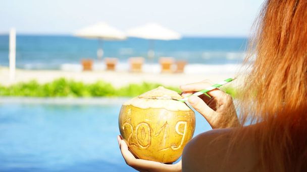 Chica con cuernos de venado de año nuevo beber coco con 2019 dibujo en la playa
 - Foto, imagen