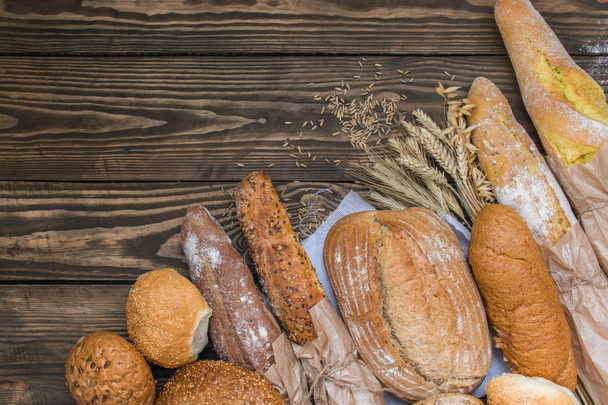 Vers gebakken broodproducten op houten achtergrond - Foto, afbeelding