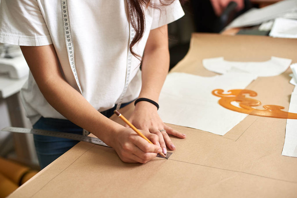 Рабочее место в дизайнерской студии, профессиональные женщины-дизайнеры делают бумажные узоры с помощью измерительной ленты, линейки и кривых
 - Фото, изображение