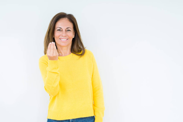 Красивая женщина средних лет в жёлтом свитере на изолированном фоне делает итальянский жест с уверенным выражением рук и пальцев
 - Фото, изображение