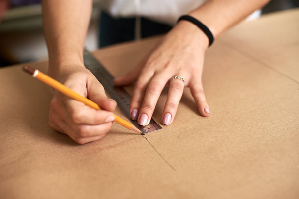 Local de trabalho em estúdio de design, designer profissional do sexo feminino fazendo padrões de papel usando fita métrica, régua e curvas
 - Foto, Imagem