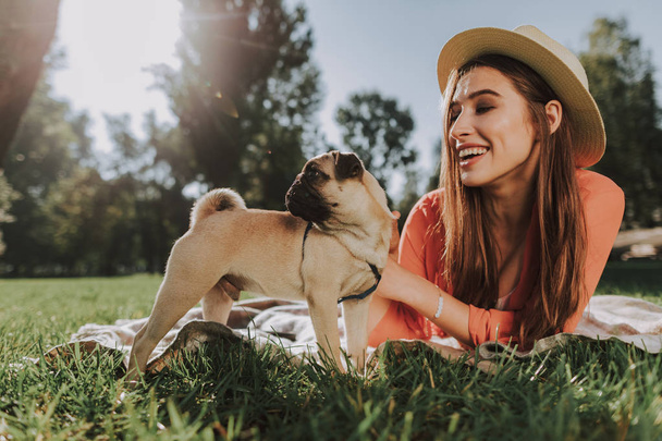 Smiling woman is lying on plaid with her dog - Foto, afbeelding