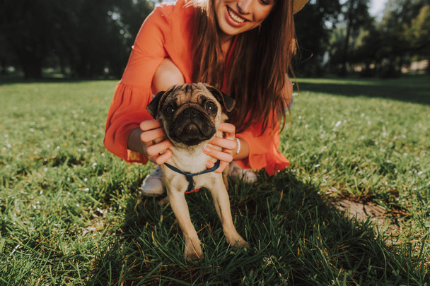 Young smiling woman is sitting on grass with her dog - Foto, Imagen