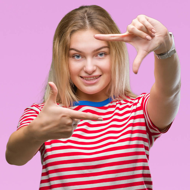 Young caucasian woman over isolated background smiling making frame with hands and fingers with happy face. Creativity and photography concept. - Photo, image