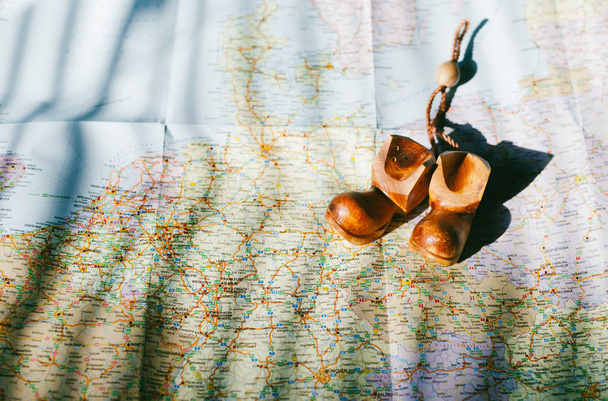 ヴィンテージ レトロな色で旅行者の道路地図のクローズ アップ。茶色のお土産カラフルなマップ上の木製の靴。ブラインドの影 - 写真・画像