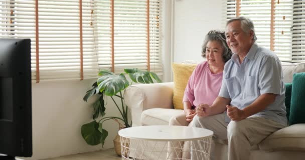 Asian senior couple watching television movie with excite emotion together in living room. - Filmmaterial, Video