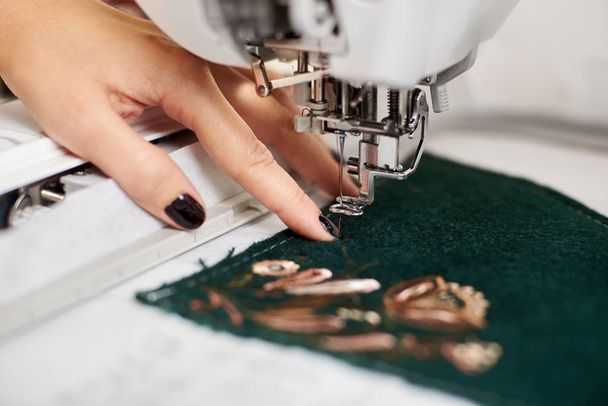 Close up van vrouw gemanicuurde hand bezig met naaimachine  - Foto, afbeelding