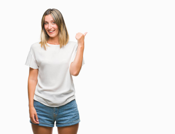 Young beautiful woman over isolated background smiling with happy face looking and pointing to the side with thumb up. - Foto, immagini
